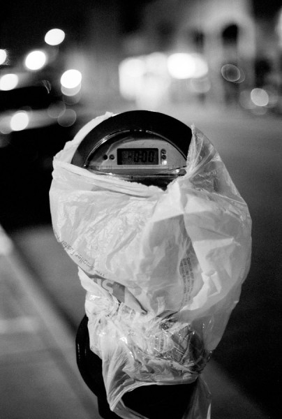 A park meter wrapped in plastic in the middle of the night